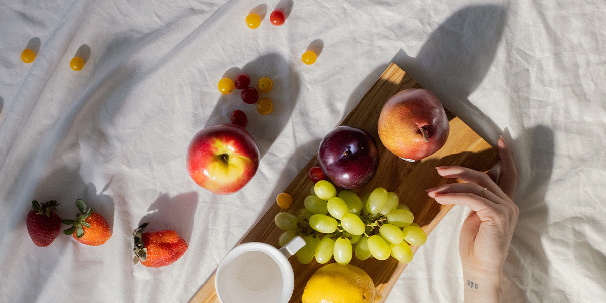 Fruit spread out on a white blanket and illuminated from the side by sunlight