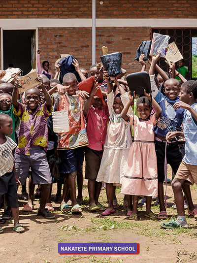 Children in Malawi sit on the ground surrounded by corncobs and look at the camera