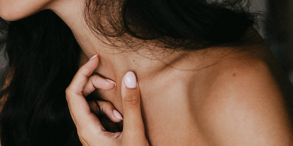 Décolleté of a dark-haired woman gently touching her skin