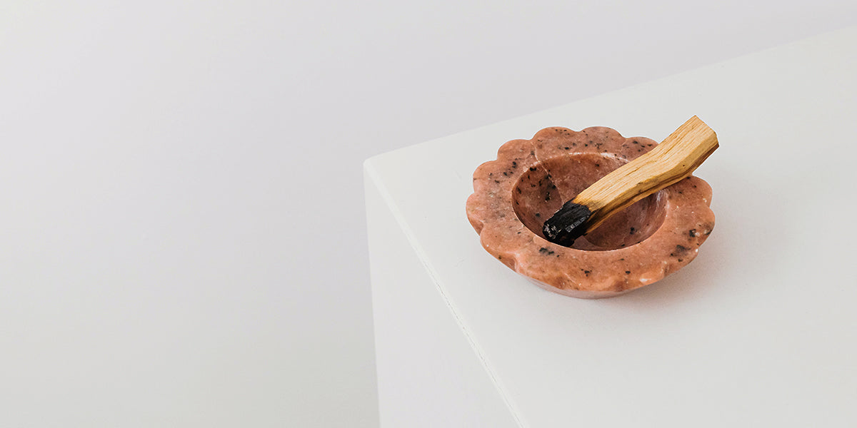 A piece of sandalwood in a ceramic bowl on a white table.