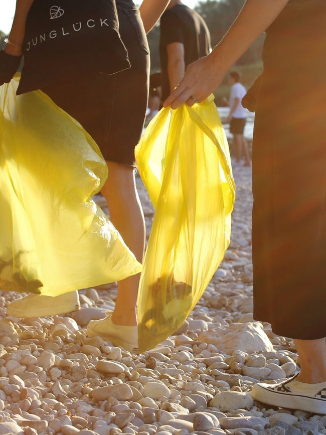 People walking on gravel and carrying garbage bags on World Clean Up Day.