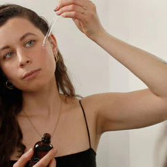 Woman applies serum to the face with a pipette