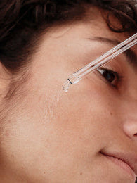 Woman applies serum to the face with a pipette